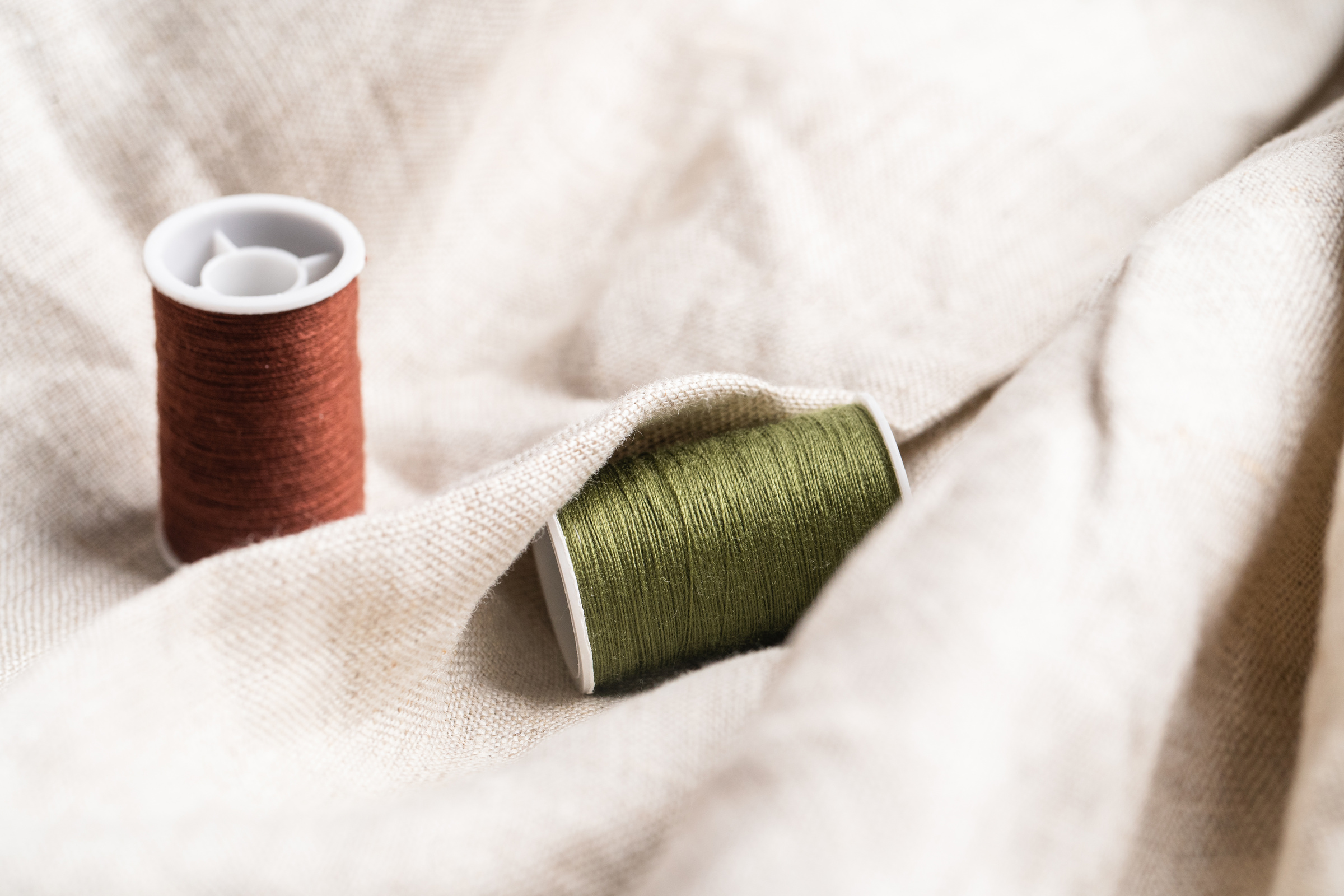 Green and Brown Spools of Thread on Fabric